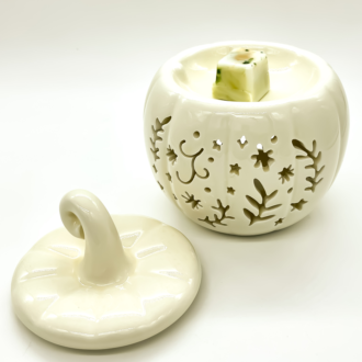Quemador de cera con forma de calabaza blanca calada, con la tapa retirada mostrando el cuenco superior